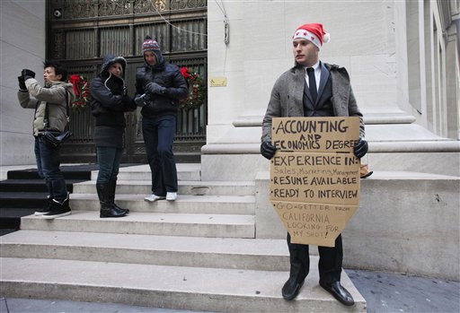In this Dec. 15, 2010 photo, Jesse Paloger holds up a sign while standing on Wall Street as he hopes to find a job, in New York. Paloger, who has an accounting and economics degree from the University of California, Santa Barbara, has written on the bottom of his sign, "Go-getter from California looking for my shot!" Fewer people applied for unemployment benefits last week, the third drop in the past four weeks and a sign that the job market is slowly improving.   (AP Photo/Mark Lennihan) (AP)