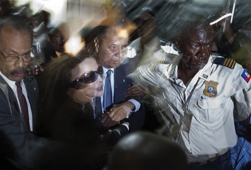 ** CORRECTS NAME OF WIFE TO VERONIQUE ROY ** Haiti's former dictator Jean-Claude "Baby-Doc" Duvalier, center, and his wife Veronique Roy are helped by a police officer as they are surrounded by reporters upon their arrival to the Toussaint Louverture international airport in Port-au-Prince, Haiti, Sunday Jan. 16, 2011. Duvalier returned to Haiti after nearly 25 years in exile, a surprising and perplexing move that comes as his country struggles with a political crisis and the stalled effort to recover from last year's devastating earthquake. (AP Photo/Ramon Espinosa) (AP)