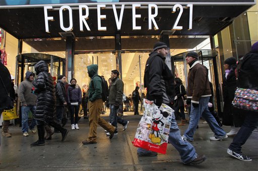 FILE - In this Dec. 26, 2010 file photo, people walk past a Forever 21 store in New York's Times Square. The population of the U.S. has grown by 8 million people since the previous record was set. That means there were millions more shoppers in stores this Christmas, driving up the sales total. But the average amount of spending per person was down from a few years ago, suggesting consumers are still slower to pull out their wallets. (AP Photo/Mary Altaffer, file) (AP)