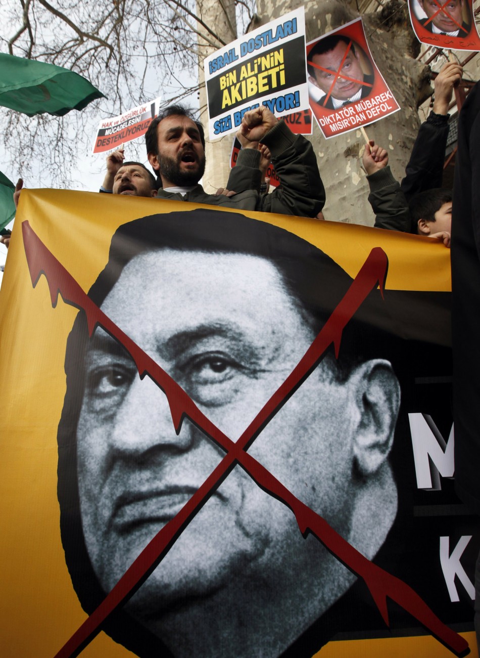 Egyptian protesters holding a sign with President Hosni Mubarak's face crossed out.