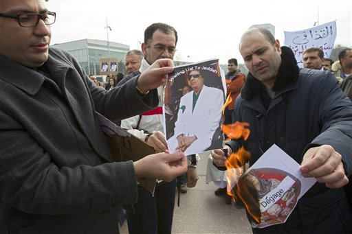 Protesters burn photos of Libyan leader Moammar Ghaddafi during a demonstration to support the Libyan people, on Place des Nations in front of the European headquarters of the United Nations, in Geneva, Switzerland, Saturday, Feb. 19, 2011. (AP Photo/Keystone, Salvatore Di Nolfi) (AP)