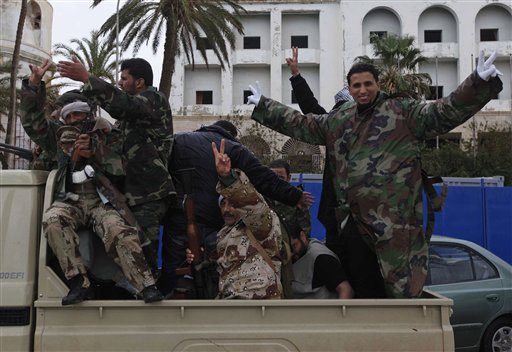 Libyan gunmen flash the V sign as they stand on a military vehicle driving in the streets of  Benghazi, Libya, on Friday Feb. 25, 2011. Several tens of thousands held a rally in support of the Tripoli protesters in the main square of Libya's second-largest city, Benghazi, where the revolt began, about 580 miles (940 kilometers) east of the capital along the Mediterranean coast.  (AP Photo/Hussein Malla) (AP)
