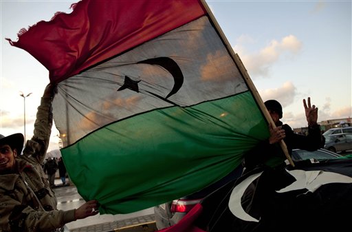 Libyan men hold the former royal flag as they drive past a demonstration against Libyan leader Moammar Gadhafi in Benghazi, in eastern Libya, Sunday, Feb. 27, 2011. (AP Photo/Kevin Frayer) (AP)