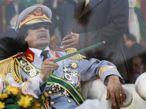 FILE - In this Sept. 1, 2009 file photo, Libyan leader Moammar Gadhafi gestures with a green cane as he takes his seat behind bulletproof glass for a military parade in Green Square, Tripoli, Libya. Libyan protesters celebrated in the streets of Benghazi on Monday, Feb. 21, 2011 claiming control of the country's second largest city after bloody fighting, and anti-government unrest spread to the capital with clashes in Tripoli's main square for the first time. Moammar Gadhafi's son vowed that his father and security forces would fight "until the last bullet." (AP Photo/Ben Curtis, FIle) (AP)