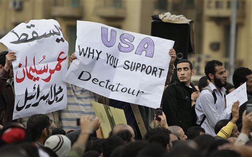 Anti-government protesters carry posters in English reading "USA, why you support dictator", center, referring to Egyptian President Hosni Mubarak and in arabic reading "Down Omar Suleiman, Israel's man", referring to the recently-named Egyptian Vice-President, left, at the demonstration in Tahrir square in downtown Cairo, Egypt, Sunday, Jan. 30, 2011. (AP Photo/Ben Curtis) (AP)