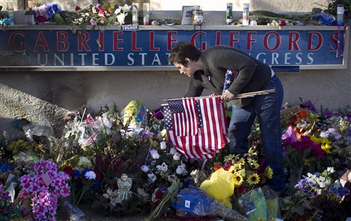 Amanda Sapir picks up flags left at a memorial outside Rep. Gabrielle Giffords Tucson office on Friday, Feb. 4, 2011 in Tucson, Ariz.  Volunteers dismantled a massive tribute Friday outside the Tucson hospital where U.S. Rep. Gabrielle Giffords and other victims of a mass shooting were treated.  The volunteers removed thousands of candles, cards, photos, stuffed animals and flowers that blanketed the 60 foot-by-100 foot lawn in front of University Medical Center, where doctors performed life-saving surgery on the Arizona congresswoman, who is now in a rehabilitation facility in Houston. The items filled up 60 boxes, which will be stored in a locked area at the hospital until a permanent memorial can be built, hospital spokeswoman Darci Slaten said.  (AP Photo/ The Arizona Republic, Pat Shannahan) (AP)