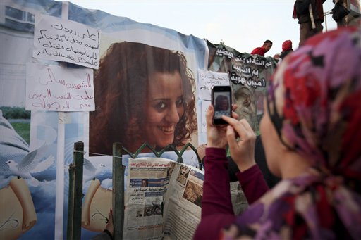 An anti-government protester takes a picture of a poster of Sally Zahran, age 23, who was killed in southern Egypt last month during clashes, in Tahrir Square, in Cairo, Egypt, Tuesday, Feb. 8, 2011. Faces of some of the hundreds killed in Egypt's two-week-old uprising are beginning to emerge from the fog of chaos. Details of the lives lost have started to appear in Egyptian newspapers, on websites and in huge posters put up in Cairo's Tahrir Square, the center of the revolt that erupted Jan. 25. The paper next to the photo reads in Arabic "Sally the martyr. She taught Egyptian people the meaning of manhood". (AP Photo/Tara Todras-Whitehill) (AP)