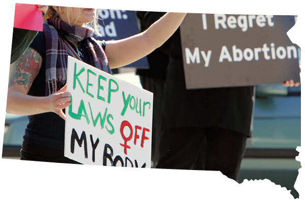 A demonstrator holds up a pro-choice sign, left, as an opposing demonstrator holds up sign reading "I Regret My Abortion", during a rally in downtown Sioux Falls, S.D.