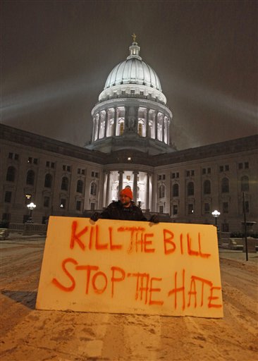 Luke Balsavich holds a large sign outside the state Capitol Monday, Feb. 21, 2011, in Madison, Wis. Opponents to Governor Scott Walker's bill to eliminate collective bargaining rights for many state workers are taking part in their seventh day of protesting.  (AP Photo/Jeffrey Phelps) (AP)
