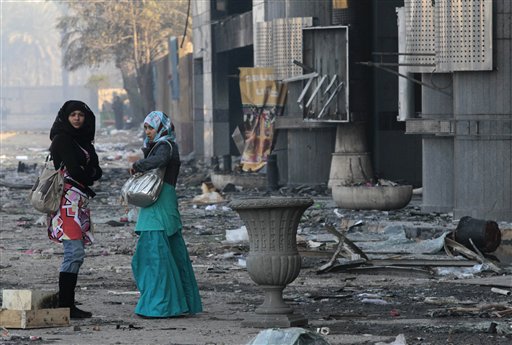 Women walk past a damaged shopping center in Cairo, Egypt, Monday, Jan. 31, 2011. Police and garbage collectors appeared on the streets of Cairo Monday morning and subway stations reopened after soldiers and neighborhood watch groups kept the peace in many districts overnight. (AP Photo/Lefteris Pitarakis) (AP)