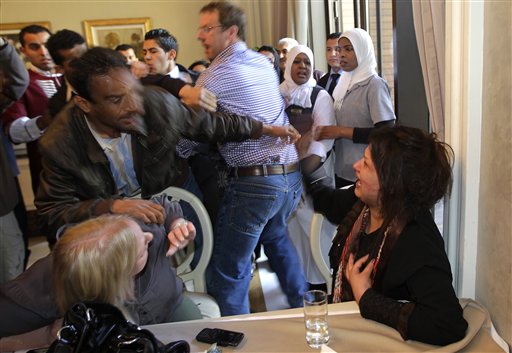 A Ministry of Information official, left, tries to grab Iman Al-Obeidi, who said she spent two days in detention after being arrested at a checkpoint in Tripoli, Libya,  and was sexually assaulted by up to 15 men while in custody  in Tripoli Saturday March 26, 2011, after storming into the hotel's breakfast room to show her wounds to foreign media. A scuffle between hotel employees, information ministry officials and plain clothed police trying to grab her and stop the press for filming on one side and foreign media representatives followed. Two cameras were smashed on the ground and at least one reporter was beaten and kicked.  Al-Obeidi was later taken in a car to an undisclosed location. Center is an unidentified foreign journalist . (AP Photo/Jerome Delay) (AP)