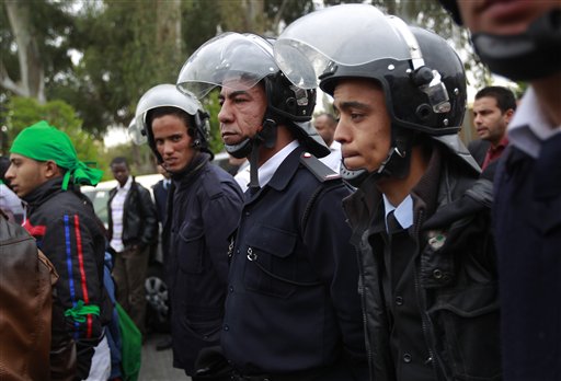 Libyan police stand in front of a group of women supporting Moammar Gadhafi staging a demonstration on the front doors of the Rixos hotel where foreign journalists are staying in Tripoli, Libya, Saturday March 19, 2011. Moammar Gadhafi warned international forces they would "regret" intervening in Libya and his troops attacked the heart of the 5-week-old uprising on Saturday, swarming the first city seized by the rebels with shells, gunfire and warplanes. (AP Photo/Jerome Delay) (AP)