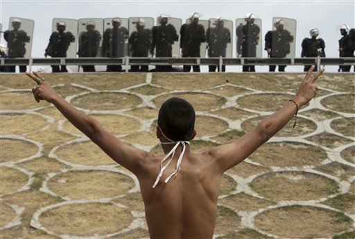 A Bahraini anti-government protester gestures in front of riot police on an overpass near Pearl roundabout Sunday, March 13, 2011, in Manama, Bahrain. (AP Photo/Hasan Jamali) (AP)