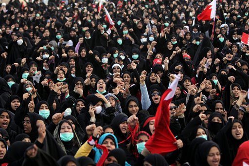 Bahraini anti-government protesters react Monday, March 14, 2011, at Pearl roundabout in Manama, Bahrain, when Shiite opposition leader Sheik Habib al-Muqdad (unseen) advised them Saudi forces were believed to be coming to the roundabout and that there were buses waiting to take them home. The women, many with masks ready for tear gas, refused to go. A Saudi-led military force crossed into Bahrain to prop up the monarchy against widening demonstrations that have sent waves of fear through Gulf states over the potential for enemy Iran to take a new foothold on their doorsteps. The barrier in the foreground reads: "Down with Hamad." (AP Photo/Hasan Jamali) (AP)