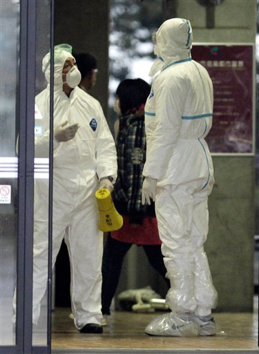 Officials wearing protective suits chat as they usher people through a radiation emergency scanning center in Koriyama, Japan, Tuesday, March 15, 2011 four days after a giant quake and tsunami struck the country's northeastern coast. (AP Photo/Mark Baker) (AP)
