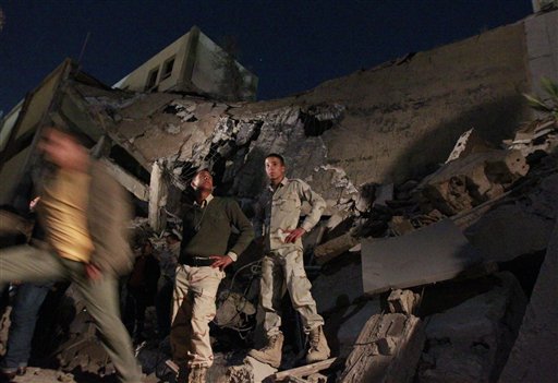 Libyan soldiers survey the damage to an administrative building hit by a missile late Sunday in the heart of Moammar Gadhafi's Bab Al Azizia compound in Tripoli, Libya, early Monday, March 21, 2011 as they are pictured during an organized trip by the Libyan authorities. (AP Photo/Jerome Delay) (AP)