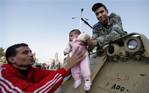 An Egyptian man hands his child to an army soldier in order to take a picture of him on top of an army personal carrier during Friday demonstration at Tahrir square in Cairo, Egypt Friday, March 4, 2011. Egypt's new prime minister designate Essam Sharaf has vowed before thousands of mostly young demonstrators at a central Cairo square that he'll do everything he can to meet their demands, pleading they turn their attention to "rebuilding" the country. (AP Photo/Nasser Nasser) (AP)