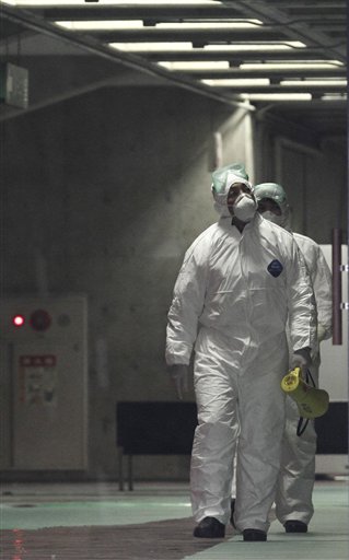 Officials wearing clothing to protect against radiation work in a center to scan residents who have been within 20 kilometers of the Fukushima Dai-ichi nuclear plant damaged by Friday's earthquake Tuesday, March 15, 2011, in Koriyama, Fukushima Prefecture, Japan. (AP Photo/Gregory Bull) (AP)