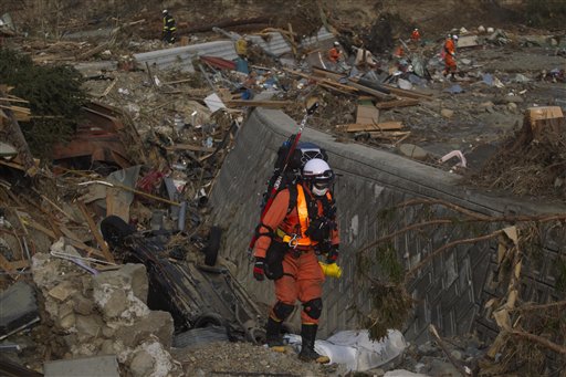 A Japanese rescue team member walks through the completely leveled village of Saito, in northeastern Japan, Monday, March 14, 2011. (AP Photo/David Guttenfelder) (AP)