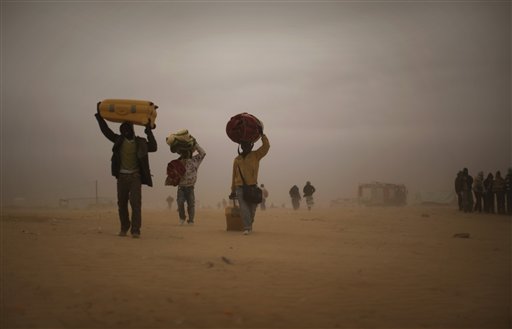 Men, who used to work in Libya and fled the unrest in the country, carry their belongings as they walk during a sand storm in a refugee camp at the Tunisia-Libyan border, in Ras Ajdir, Tunisia, Tuesday, March 15, 2011. More than 250,000 migrant workers have left Libya for neighboring countries, primarily Tunisia and Egypt, in the past three weeks. (AP Photo/Emilio Morenatti) (Associated Press)