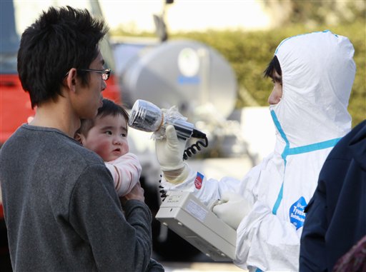 A man holds his baby as they are scanned for levels of radiation in Koriyama, Fukushima Prefecture, Japan, Sunday, March 13, 2011. Friday's quake and tsunami damaged two nuclear reactors at a power plant in the prefecture, and at least one of them appeared to be going through a partial meltdown, raising fears of a radiation leak. (AP Photo/Mark Baker) (AP)