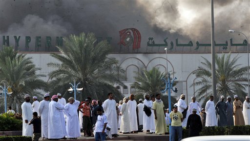 CORRECTS TO REMOVE EXTRANEOUS INFORMATION FROM CAPTION FIELD Omani nationals watch smoke rise from Lulu hypermarket in Sohar, Oman, Monday Feb. 28, 2011. Omani security forces have blocked roads to Sohar, about 120 miles (200 kilometers) northwest of the capital of Muscat, after deadly clashes between pro-democracy protesters and riot police. (AP Photo) (AP)
