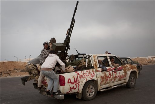 Libyan rebels jump onto the back of their vehicle as they leave Ras Lanouf, 250 km east of Sirte, central Libya, Tuesday, March 29, 2011. Gadhafi's forces drove the rebels out of Bin Jawwad, a hamlet east of Sirte, on Tuesday. Cars and trucks of the retreating rebels filled both lanes of the highway east to the oil port of Ras Lanouf.  (AP Photo/Anja Niedringhaus) (AP)