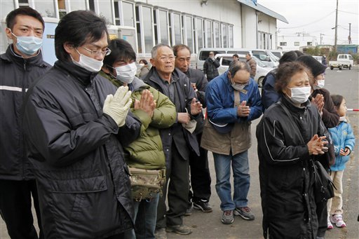 Residents pay their last respects to a victim as a van carrying the coffin leaves a temporary morgue at a bowling alley in Natori, Miyagi Prefecture Monday, March 21, 2011 as the death toll continues to rise following the March 11 earthquake and tsunami that devastated the northeast coast of Japan.  (AP Photo/Mark Baker) (AP)