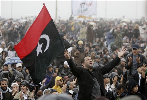 An anti-Libyan Leader Moammar Gadhafi protester prays as he holds the old Libyan flag, during the Friday prayer at the court square, in Benghazi, eastern Libya, Friday March 4, 2011. Fighters loyal to Moammar Gadhafi set up checkpoints in Tripoli, searching cars, ahead of planned anti-government protests Friday, raising fears of new bloodshed in the Libyan capital where a heavy crackdown the past week has spread fear among residents. (AP Photo/Hussein Malla) (AP)
