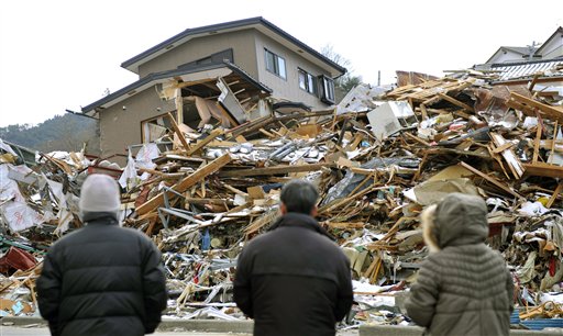 Family members stand in front of their collapsed house in Onagawa, northern Japan Friday, March 18, 2011, one week after a massive earthquake and tsunami.  (AP Photo/Kyodo News) JAPAN OUT, MANDATORY CREDIT, NO LICENSING IN CHINA, HONG KONG, JAPAN, SOUTH KOREA AND FRANCE (AP)