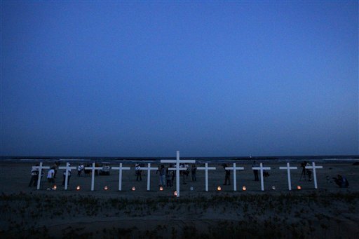 People gather near crosses -- 11 for the workers who died in the Deepwater Horizon oil rig explosion and one for the Gulf of Mexico, center -- during a vigil to mark the first anniversary of the BP PLC oil spill on a beach in Grand Isle, La., Wednesday, April 20, 2011. (AP Photo/Patrick Semansky) (AP)