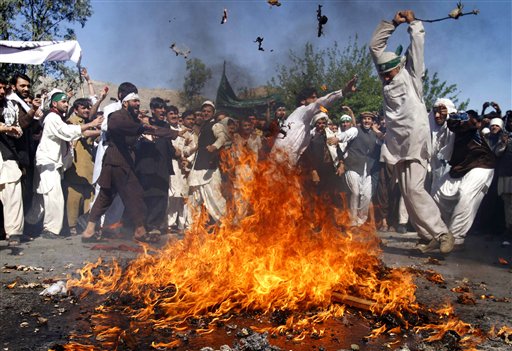 An Afghan protestor beats a burning effigy of U.S. President Barack Obama during a rally in Jalalabad, Afghanistan on Sunday, April 3, 2011. Afghan protests against the burning of a Quran in Florida entered a third day with a demonstration in the major eastern city Sunday, while the Taliban called on people to rise up, blaming government forces for any violence. (AP Photo/Rahmat Gul) (AP)