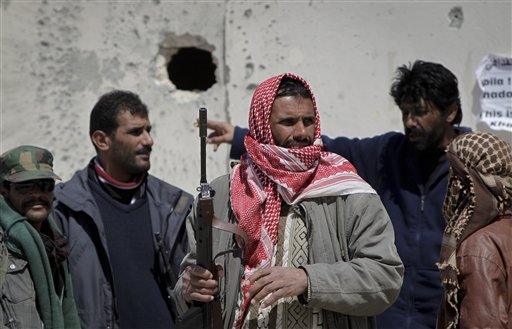 Libyan rebels look towards black smoke rising above the city amidst the sound of shelling, in Ajdabiya, Libya Sunday, April 10, 2011. Libyan rebels said NATO airstrikes on Sunday helped them drive Moammar Gadhafi's forces out of the hard-fought eastern city of Ajdabiya that is the gateway to the opposition's stronghold. (AP Photo/Ben Curtis) (AP)