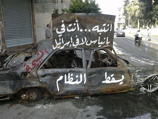 In this citizen journalism image made on a mobile phone and acquired by the AP, and taken Sunday, April 17, 2011, Arabic writing on a burnt car reads:" pay attention, you are in Banias not in Israel. Down with the regime, the "Shabiha" which is a term used in Syria to describe pro-government thugs" in the port city of Banias, Syria. Thousands of people gathered in the central Syrian city of Homs main square Monday following the funeral of six people who were shot dead a day earlier saying they will hold an open-ended sit-in until President Bashar Assad's regime is brought down, witnesses said. (AP Photo) (AP)