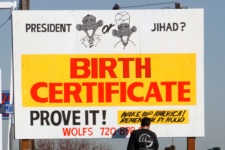 Maintenance man David Lee of Arvada, Colo., puts the finishing touches on a sign featuring President Barack Obama for a sales lot for pre-owned vehicles along Interstate 70 in the northwest Denver suburb of Wheat Ridge, Colo., on Friday, Nov. 20, 2009