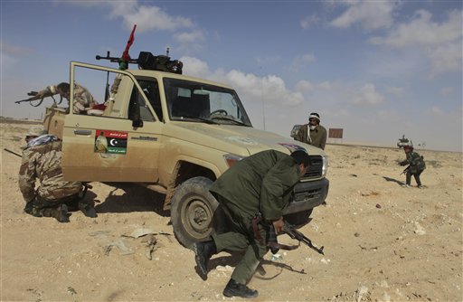 Libyan rebels run for cover after coming under heavy artillery fire from pro-Gadhafi forces along the front line near Brega, Libya, Friday, April 1, 2011. Libya's rebels will agree to a cease-fire if Moammar Gadhafi pulls his military forces out of cities and allows peaceful protests against his regime, an opposition leader said Friday as rebels showed signs that their front-line organization is improving.  (AP Photo/Altaf Qadri) (AP)