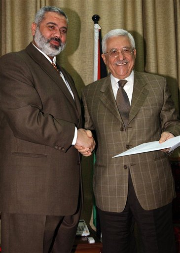 FILE - In this Sunday, March 19, 2006 file photo made available by the Palestinian Authority, the Palestinian Authority President Mahmoud Abbas, right, holds a file with the proposal for a new Palestinian Cabinet as he shakes hands with Palestinian Prime Minister Ismail Haniyeh, from the Islamic group Hamas, in Gaza City. Hamas officials said Tuesday, May 3, 2011, that the Islamic militant group would honor an unofficial truce with Israel after forming a new government with Palestinian rivals from the West Bank. (AP Photo/Abdel Alahim Abu Askar/Palestinian Authority, File) (AP)
