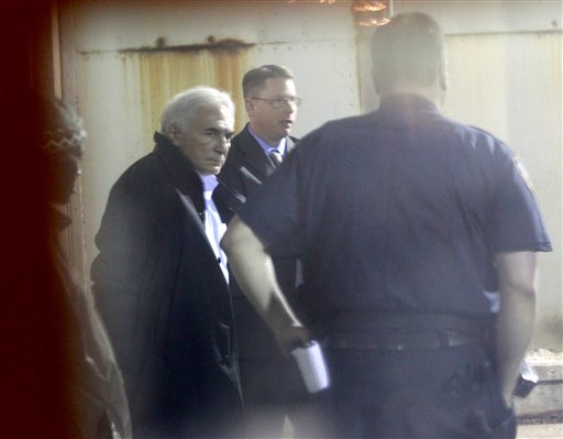 International Monetary Fund leader Dominique Strauss-Kahn, left, is seen through a window as he is checked into Municipal Court, Monday, May 16, 2011 in New York. Strauss-Kahn is accused of sexually assaulting a maid in his hotel room in New York City. (AP Photo/Julio Cortez) (AP)