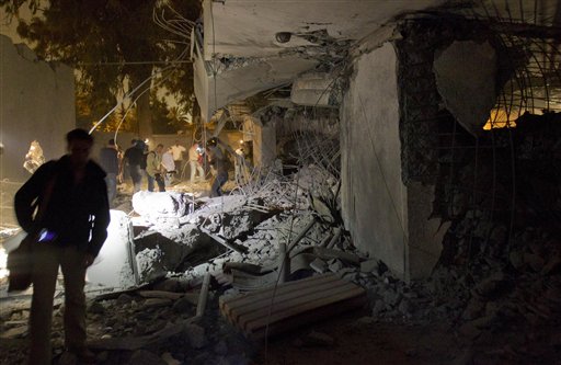 In this photo made on a government organized tour, government officials and members of the media gather at the site of a NATO missile strike that killed Gadhafi's youngest son and three grandchildren and wounded friends and relatives, in Tripoli, Libya, Saturday, April 30, 2011. Libyan leader Moammar Gadhafi survived attack, Libya's spokesman said. (AP Photo/Darko Bandic) (AP)