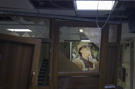 In this photo taken on a government organized tour, a poster of Libyan leader Moammar Gadhafi is seen in a damaged official building following an airstrike in Tripoli, Libya, early Tuesday, May 17, 2011. (AP Photo/Darko Bandic) (AP)