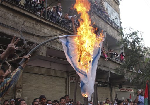 Palestinian mourners burn an Israeli flag during a funerla procession of three Palestinians who killed when Israeli soldiers opened fire on Sunday at protesters who approached the village of Majdal Shams at Syria's border with the Israeli-controlled Golan Heights, at Yarmouk Palestinian refugee camp in Damascus, Syria, on Monday May 16 2011. Israeli troops clashed with Arab protesters along three hostile borders on Sunday, leaving people dead and dozens wounded in an unprecedented wave of violence marking the anniversary of the mass displacement of Palestinians surrounding Israel's establishment in 1948. (AP Photo/Bassem Tellawi) (AP)