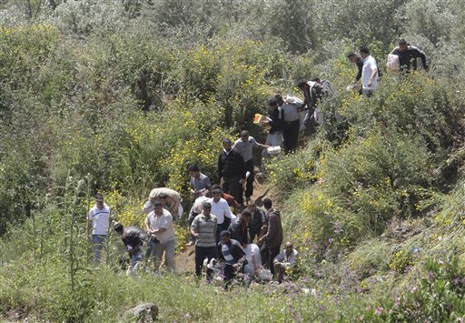Syrian citizens carry their belongings, as they cross the border illegally , fleeing from violence the western Syrian village of Talkalakh, in the Wadi Khaled area, about one kilometer (0.6 miles) from the Lebanon-Syria border, north Lebanon, Monday May 16, 2011. Carrying mattresses and bags of clothing, Syrians fleeing their homeland described a "catastrophic" scene Monday in a besieged border town that has been largely sealed off as the army tries to crush a two-month uprising. (AP Photo/Bilal Hussein) (AP)