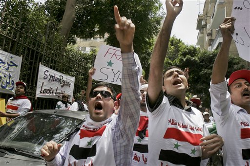 Demonstrators rally against the Syrian regime's crackdown on protesters, outside the Syrian embassy in Cairo, Egypt Tuesday, May 10, 2011. Syrian troops backed by tanks entered several southern villages near the flashpoint city of Daraa on Tuesday, according to an activist, as the Syrian government pressed its efforts to end a nationwide uprising. Writing in Arabic on t-shirts showing the Syrian flag reads "The people want to topple the regime". (AP Photo/Mohammed Abu Zaid) (AP)