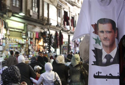 Syrians walk past a T-shirt  with a portrait of Syrian President Bashar Assad with an Arabic word read:"we love you," at a popular market in downtown Damascus , Syria, on Monday, May 30, 2011.  Syrian troops shelled a town in the center of the country Monday, and for the first time in the two-month-old revolt against the president, residents armed with automatic rifles and rocket-propelled grenades put up fierce resistance, activists said. State media said four soldiers were killed. (AP Photo/Bassem Tellawi) (AP)