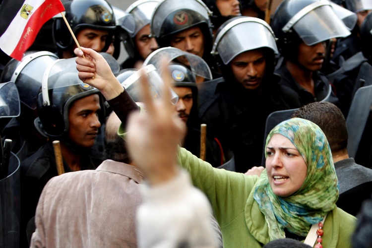 A woman holds an Egyptian flag in front of riot police during a protest in Cairo January 26, 2011. Thousands of Egyptians defied a ban on protests by returning to Egypt's streets on Wednesday and calling for President Hosni Mubarak to leave office, and some scuffled with police.  REUTERS/Asmaa Waguih (EGYPT - Tags: CIVIL UNREST POLITICS) (Â© Asmaa Waguih / Reuters)