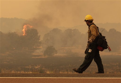 Firefighter Rigoberto Torres, of Orange Cove, Calif., walks along the road while watching a flame during the Wallow fire in the Apache-Sitgreaves National Forest near Springerville, Ariz., Tuesday, June 7, 2011. Officials say the blaze has already burned 486 square miles and winds have been driving the flames 5 to 8 miles a day since the fire began a week ago. (AP Photo/Jae C. Hong) (AP)
