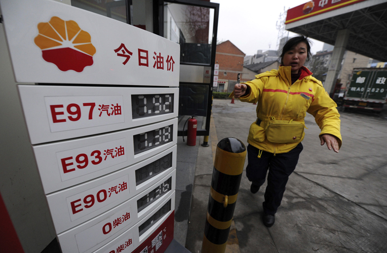 An employee gestures to stop a photographer from taking pictures near a board showing recently increased fuel prices at a gas station in Hefei, Anhui province April 7, 2011. China will increase retail gasoline and diesel prices by 5-5.5 percent to new record highs from Thursday, the government said, easing the burden of state refiners who face international oil prices at 2.5-year highs. REUTERS/Stringer (CHINA - Tags: BUSINESS ENERGY) (Â© Jianan Yu / Reuters)
