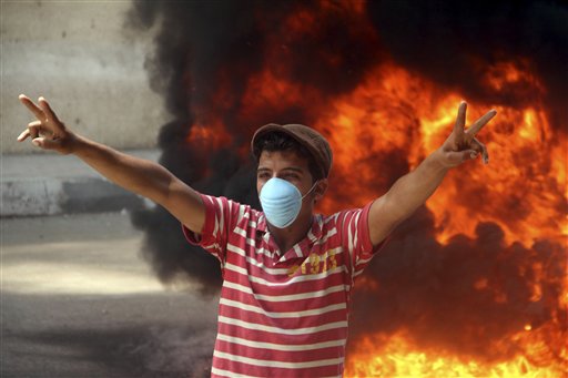 A protester wears a mask as he gestures during clashes with security forces in Cairo, Egypt, Wednesday, June 29, 2011. Egyptian security forces clashed for a second day in Cairo with hundreds of youths demanding that the country's military rulers speed up prosecution of police officers accused of brutality during mass protests that forced Hosni Mubarak to step down. More than 1,000 people have been injured, a senior official said. (AP Photo) (AP)