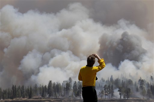 A photographer looks at smoke from a burnout fire as firefighters battle the Wallow Fire in the Apache-Sitgreaves National Forest, Ariz., Sunday, June 12, 2011. Roughly 7,000 residents of two eastern Arizona towns evacuated last week as a wildfire loomed nearby were allowed to return home Sunday as officials expressed confidence that they were making progress in their battle against the huge blaze that has been burning since May. (AP Photo/Jae C. Hong) (AP)