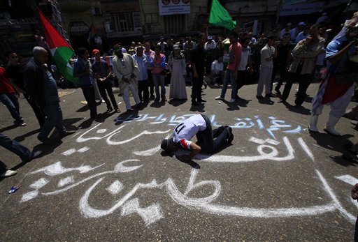 An Egyptian prays on an Arabic slogan reads " Jerusalem for us, Palestine is an Arabic land " during a protest against Israel's closure of Gaza at Tahrir Square, the focal point of Egyptian uprising, in Cairo, Egypt Friday, May 13, 2011. (AP Photo/Amr Nabil) (AP)